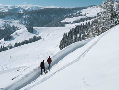 Zwei Winterwanderer die durch die SkiWelt Ellmau-Going wandern.
