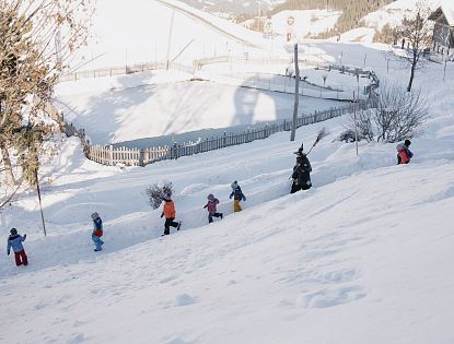 Die Hexen gehen mit den Kindern durch den verschneiten Winterwanderweg.