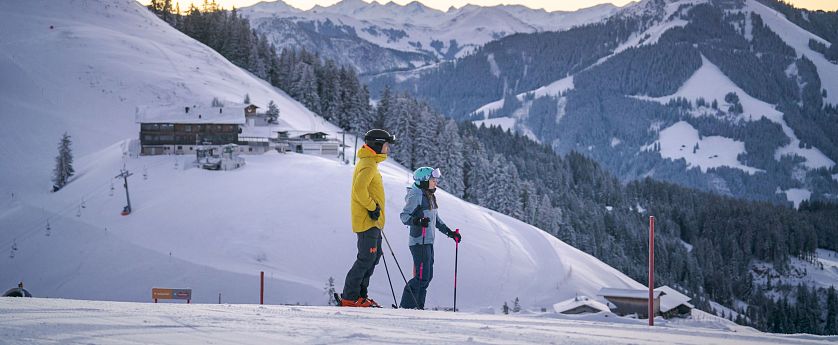 Skifahrer stehen am Hang und betrachten die Berge um sich herum.