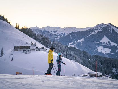 Skifahrer stehen am Hang und betrachten die Berge um sich herum.